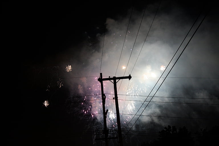 Fireworks going off behind power lines.